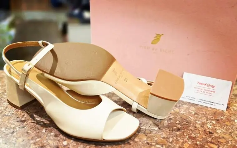 Sandales à talon crème avec ressemelage neuf, devant leur boîte d'origine